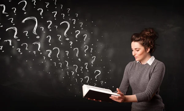 Pretty woman reading a book with question marks coming out from
