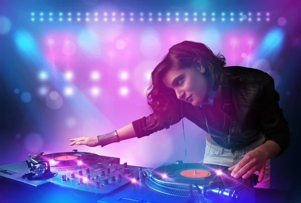 Disc jockey mixing music on turntables on stage with lights and