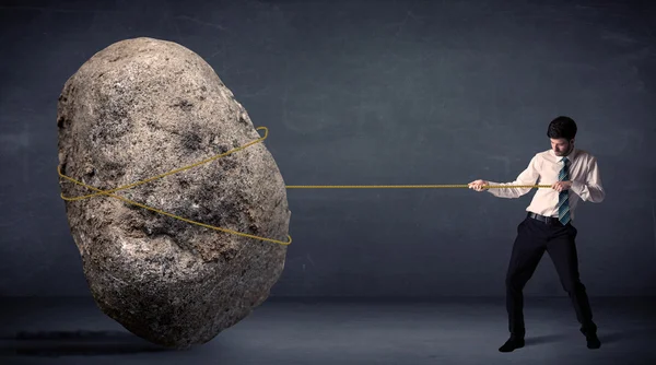 Businessman pulling huge rock with a rope