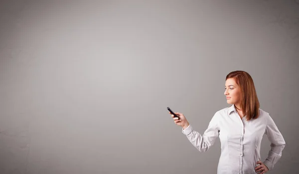 Young lady standing and holding a phone with copy space