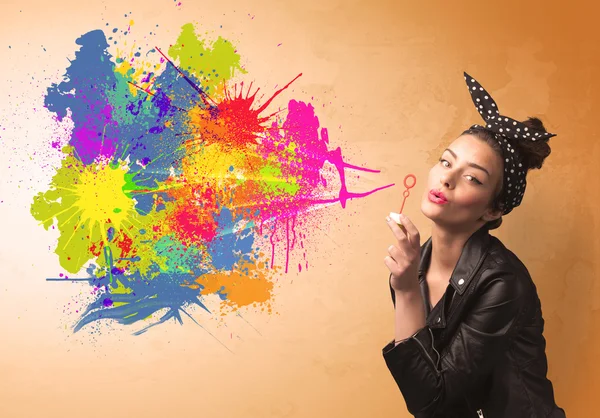 Cute girl blowing colorful splash graffiti