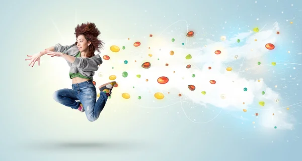 Beautiful woman jumping with colorful gems and crystals on the b