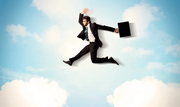 Business person jumping over clouds in the sky