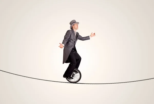 Extreme business man riding unicycle on a rope