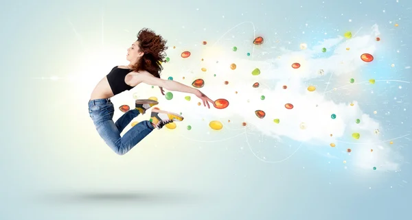 Beautiful woman jumping with colorful gems and crystals on the b