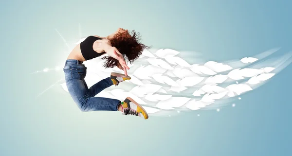 Healthy young woman jumping with feathers around her