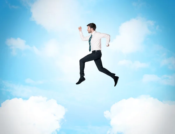 Business person jumping over clouds in the sky