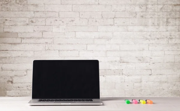 Business laptop with white brick wall