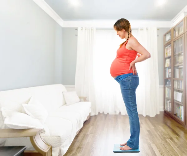A cute pregnant woman standing on scale