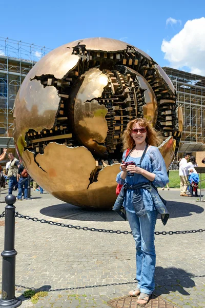 A tourist stands in front of the Sphere within a Sphere in Vatic