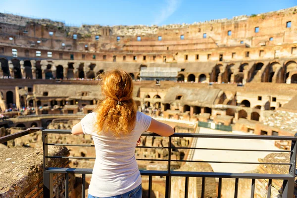 The golden-haired female tourist looks at the Colosseum, Rome