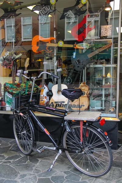 Parked bicycle in front of shop window with different types of g
