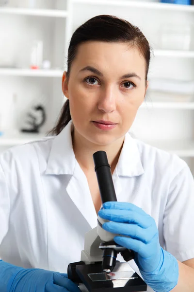 Woman in a laboratory microscope with microscope slide in hand