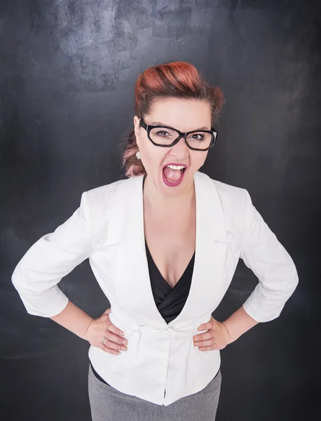 Angry screaming woman on blackboard background