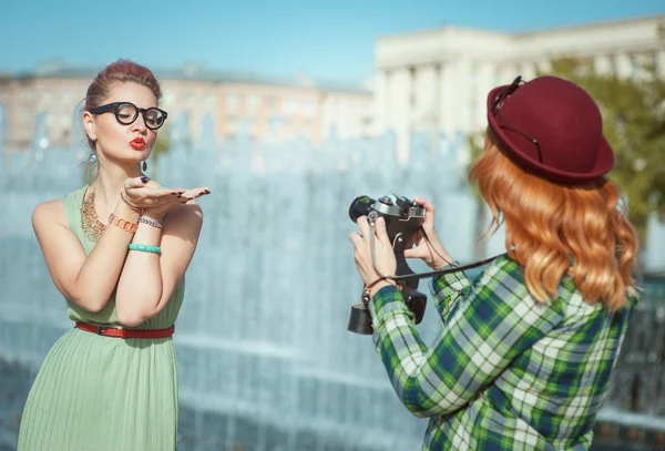 Two beautiful hipster girls taking pictures on an old camera