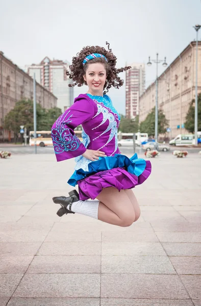 Young beautiful girl in irish dance dress and wig jumping