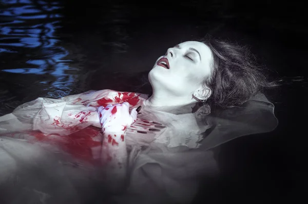 Young beautiful drowned woman in bloody dress
