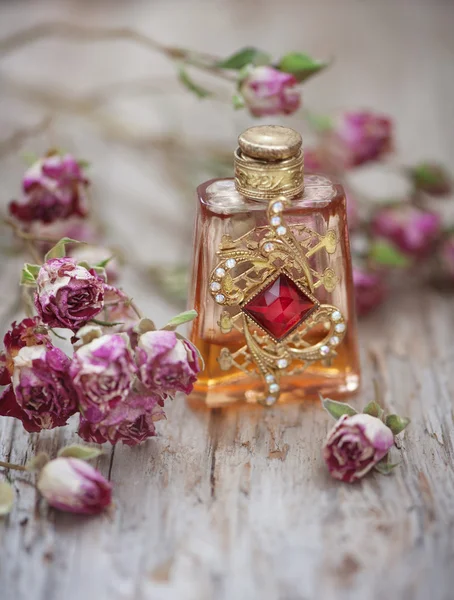Dry tea roses and vintage perfume bottle on the old wood