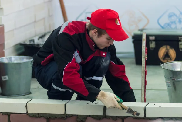 Young bricklayer performs a task of competition