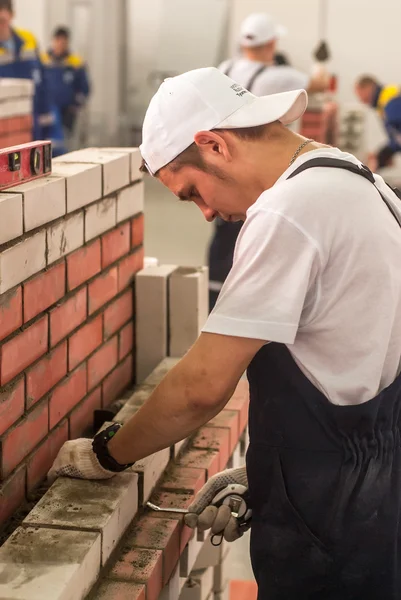 Young bricklayer performs a task of competition