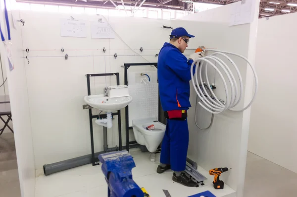 Young plumber installs equipment for bathroom