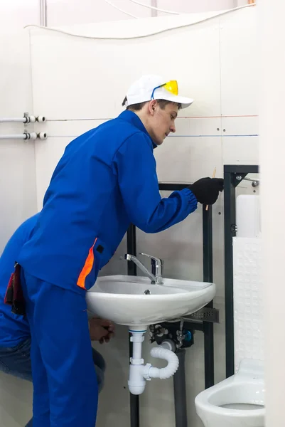 Young plumber installs equipment for bathroom