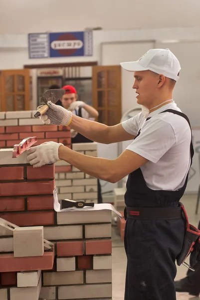 Young bricklayer performs a task of competition