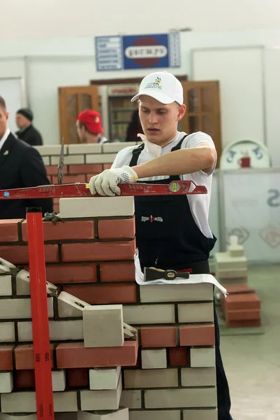 Young bricklayer performs a task of competition