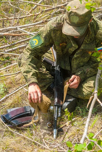 Soldier cools submachine gun barrel by water