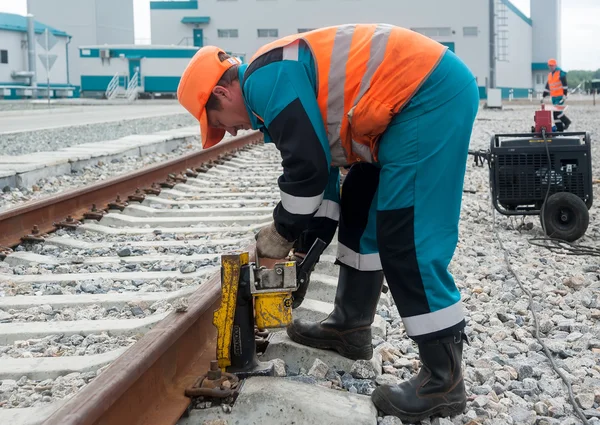 Worker establishes jack for lifting rail