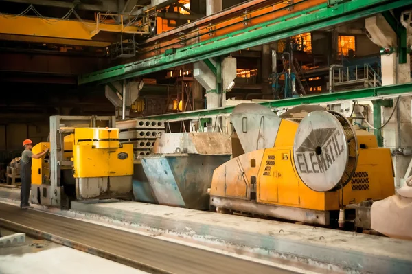 Worker works at machine on production of plates