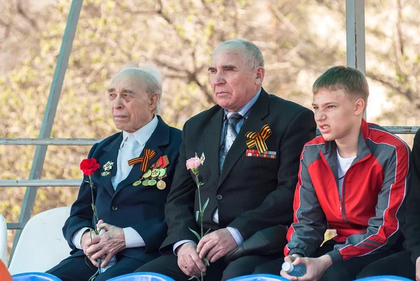 Senior veterans of World War II and boy on tribune
