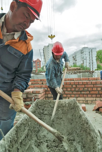 Workers knead solution for bricklayers