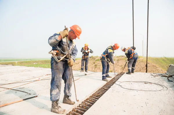 Builders with metal crow bar installing concrete panel