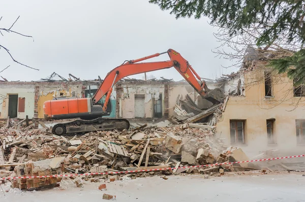 Demolition of a house with an orange digger
