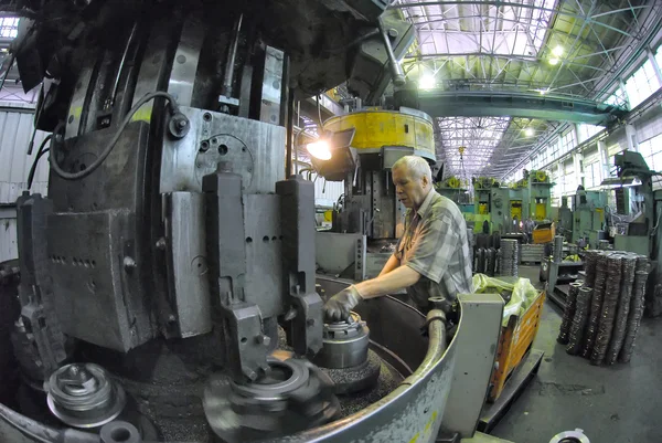 Elderly worker watches on milling machine work