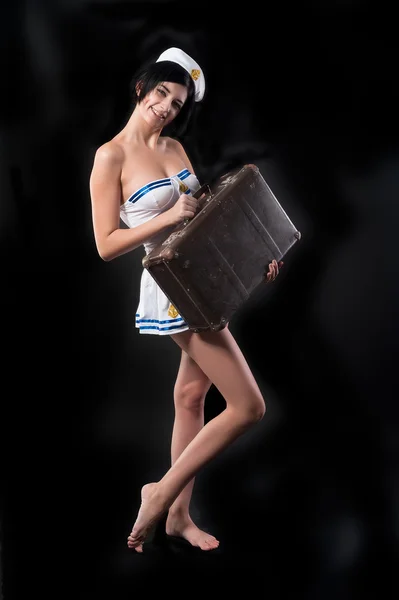 Young attractive sailor woman smiles with suitcase