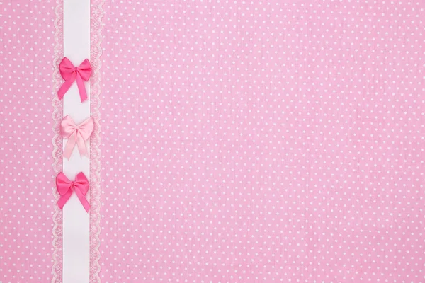 Pink polka dot textile background with ribbon and bows
