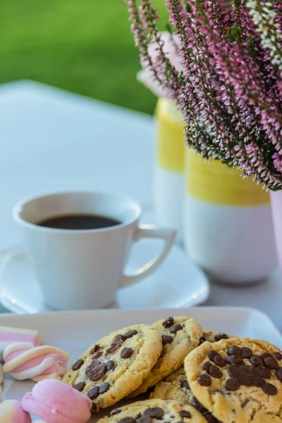 Table set with cookies, coffee and flowers in garden