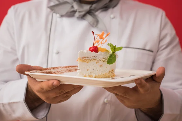 Man in chef uniform with tasty cake