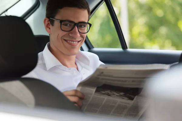 Man reading newspaper in car