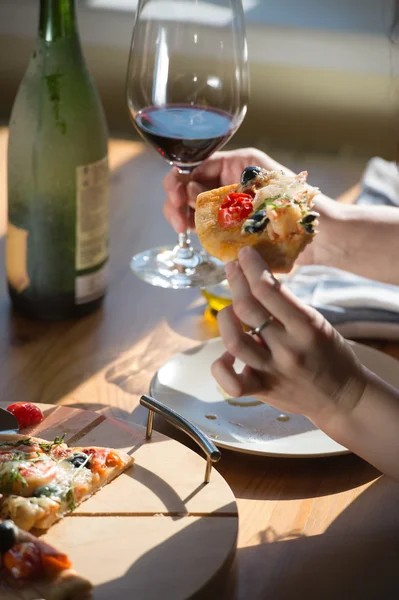 Woman eating  pizza and drinking wine
