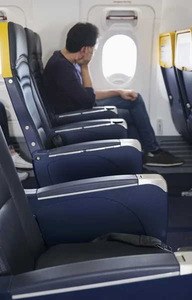 Italy, airplane cabin, passenger looking trough the emergency exit window