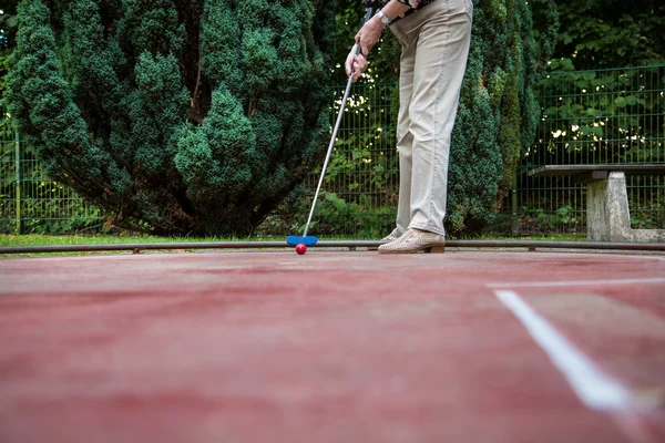 An female pensioner at the end of the minigolf court