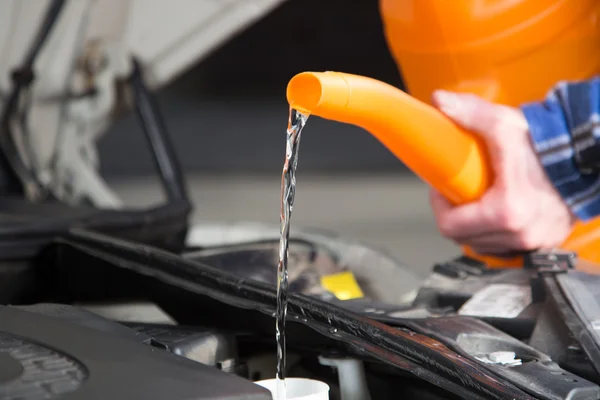 Filling freh water into the canister of the car windscreen wiper