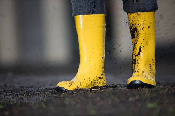 Yellow rubber boots  in a dirty puddle