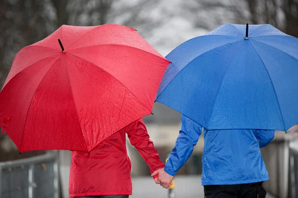 Close view from a couple hand in hand walking in the rain