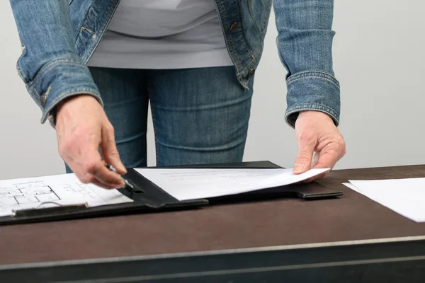 Woman reads a document which is clipped into a clipboard.