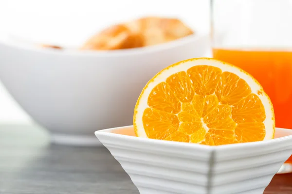 A sliced orange fruit in a bowl with a glass of orange juice and