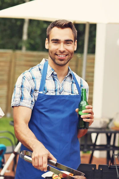 Man with beer making barbecue